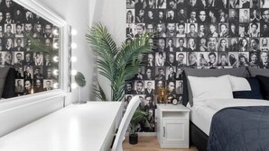 Une chambre à coucher comprenant un lit, une table de chevet et un mur décoré d’un collage de photos en noir et blanc.
