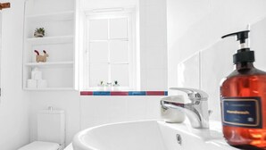 Ein Badezimmer mit einem weißen Waschbecken, einer Toilette und einem Ablagebereich für Pflegeprodukte.