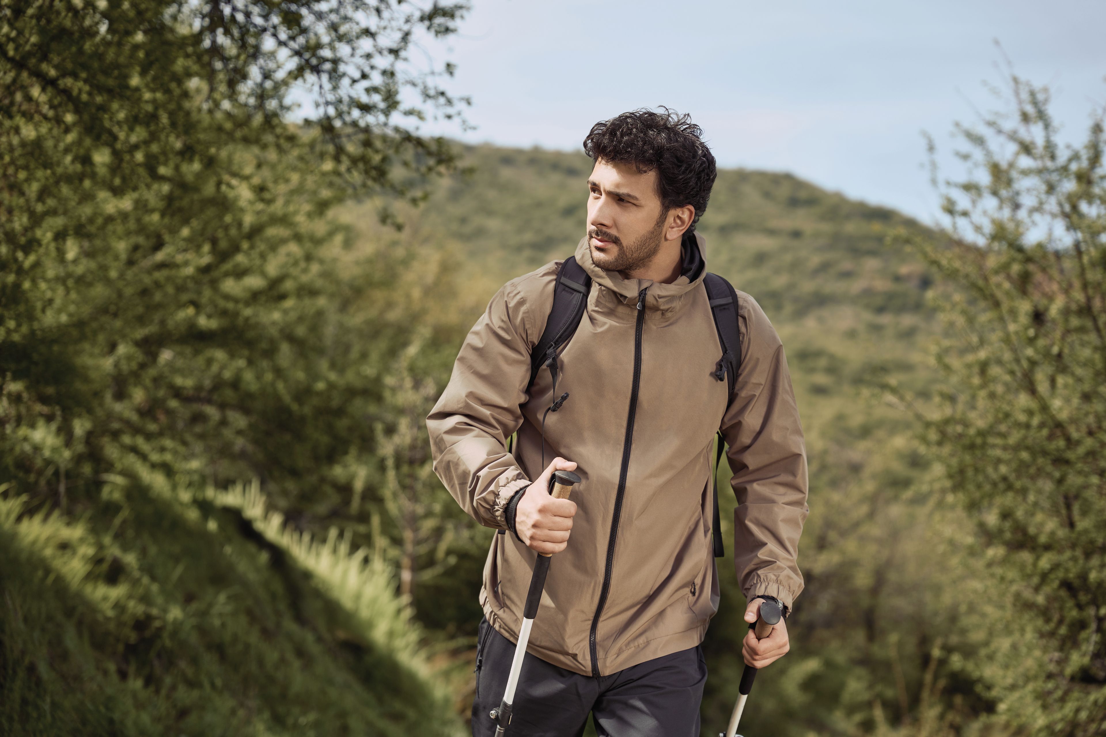 A person hiking with a backpack and walking stick in a forested area.