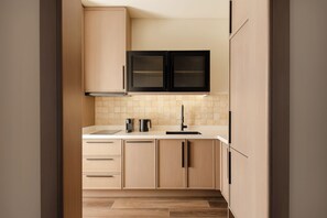 Una cocina moderna con armarios de madera clara, una campana extractora negra y un salpicadero de azulejos.