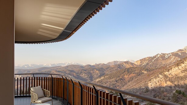 A balcony with a view of mountains, a chair, and a table. - Beldersoy Resort and Spa, Part of Destination By Hyatt (Chimgan)