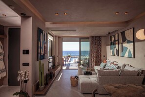 A modern living room with a view of the sea, featuring a sofa, a coffee table, and abstract art on the walls.
