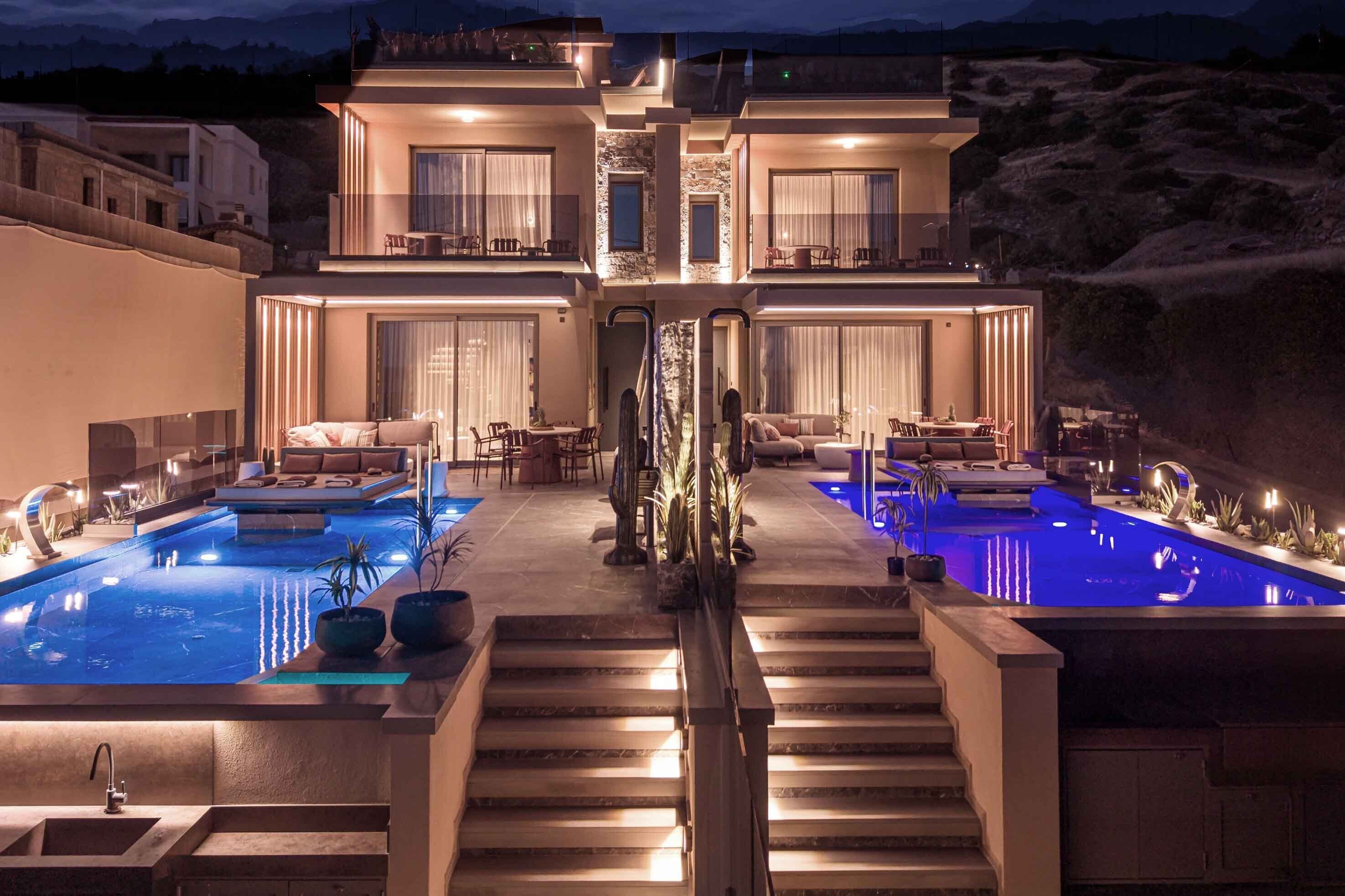 A modern two-story house with a swimming pool, outdoor seating, and a stone facade.