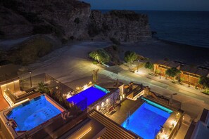 Un resort con múltiples piscinas, una playa y un acantilado con vistas al mar.