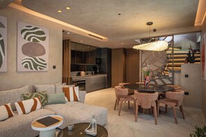 A modern living room with a sofa, coffee table, and a dining area with chairs and a table. - Lapis Nera Villa II - Beachfront & Free*Heated Pool (Heraklion)