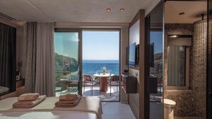 Ein Hotelzimmer mit Bett, einem kleinen Tisch mit Stühlen, einem Fernseher und einem Badezimmer mit Dusche.