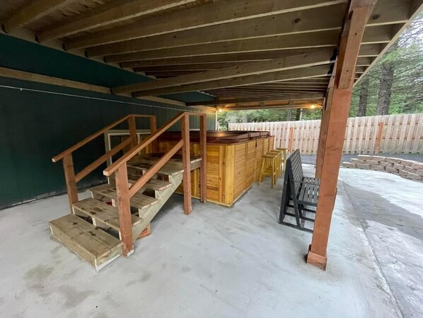 A covered outdoor area with a wooden staircase, a bar counter, and a seating area.