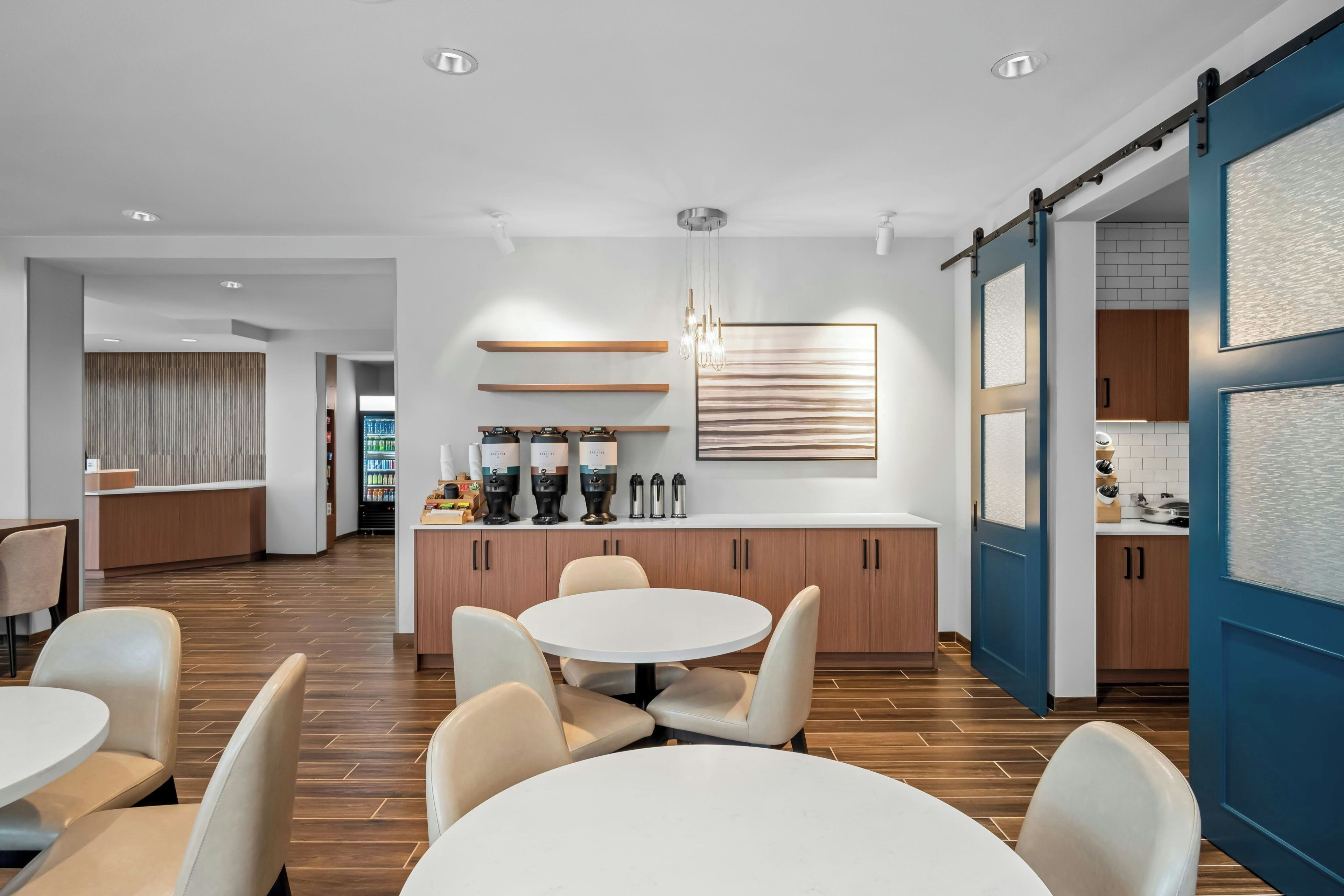 A modern kitchen with a central island, wooden cabinets, and a hanging light fixture.