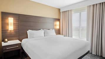 Una habitación de hotel con una cama grande, mesitas de noche, una lámpara y una ventana con cortinas.
