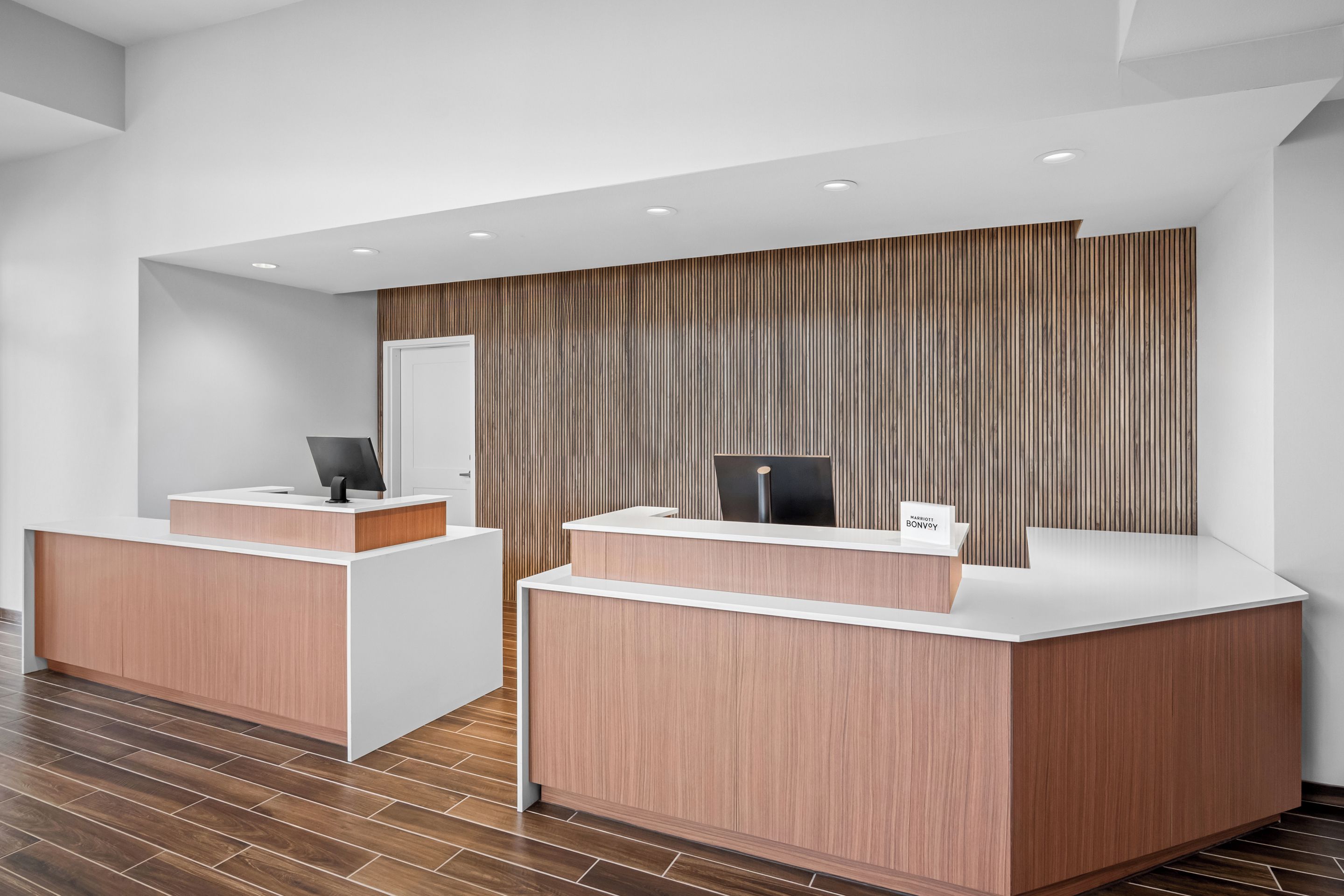 A reception area with two reception desks, a wooden panel wall, and a tiled floor.