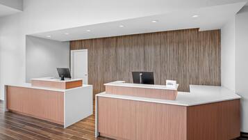 A reception area with two reception desks, a wooden panel wall, and a tiled floor.