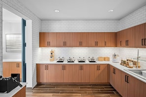 Una cocina moderna con azulejos tipo metro blancos, armarios de madera y una campana extractora de acero inoxidable.