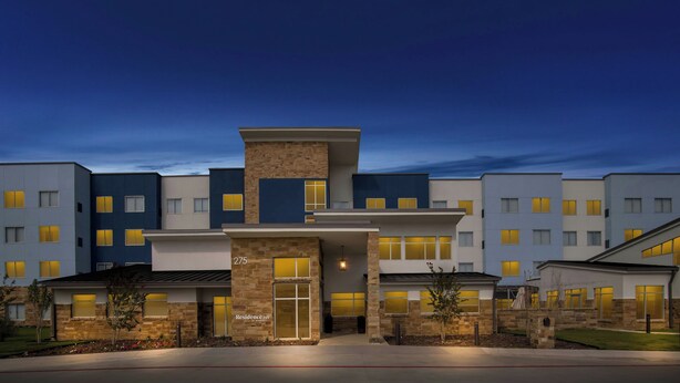 A modern hotel with a stone facade, multiple windows, and a clear sky. - Residence INN BY Marriott Waxahachie (Waxahachie)
