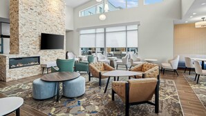 Un'area lounge moderna con parete in pietra, televisore a schermo piatto e camino. Sono disponibili diverse opzioni di seduta, tra cui divani e poltrone.