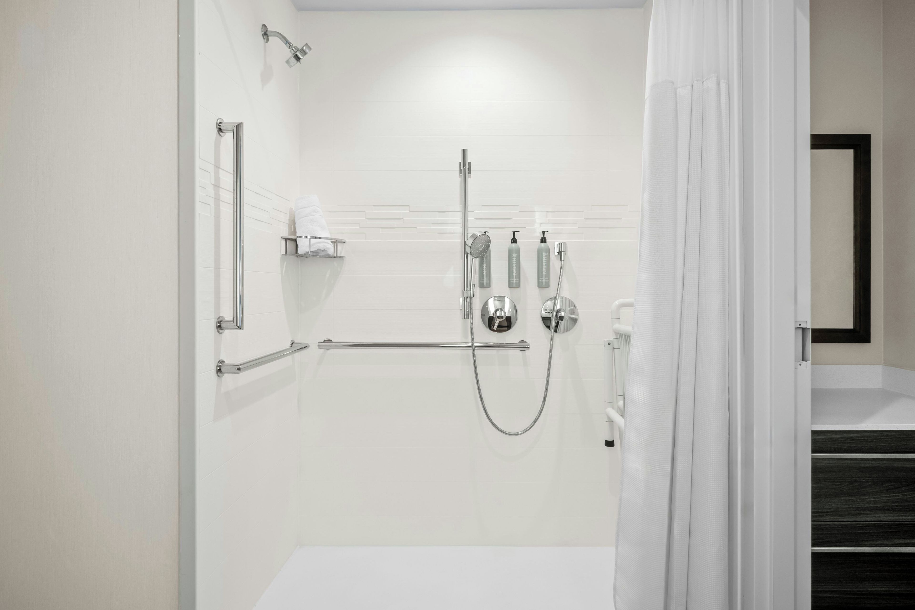 A modern bathroom with a walk-in shower, a glass shower enclosure, and a white sink.