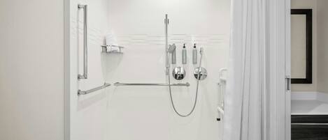 Un baño moderno con cabina de ducha a ras de suelo, cerramiento de vidrio y lavamanos blanco.