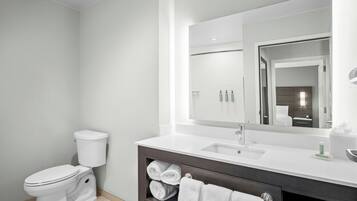 A modern bathroom with a toilet, sink, mirror, and towel rack.