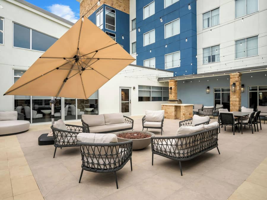 An outdoor seating area with wicker furniture, a large umbrella, and a stone fireplace.