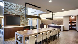 Una cocina moderna con una larga mesa de madera, electrodomésticos integrados y una pared de ladrillo decorativa.
