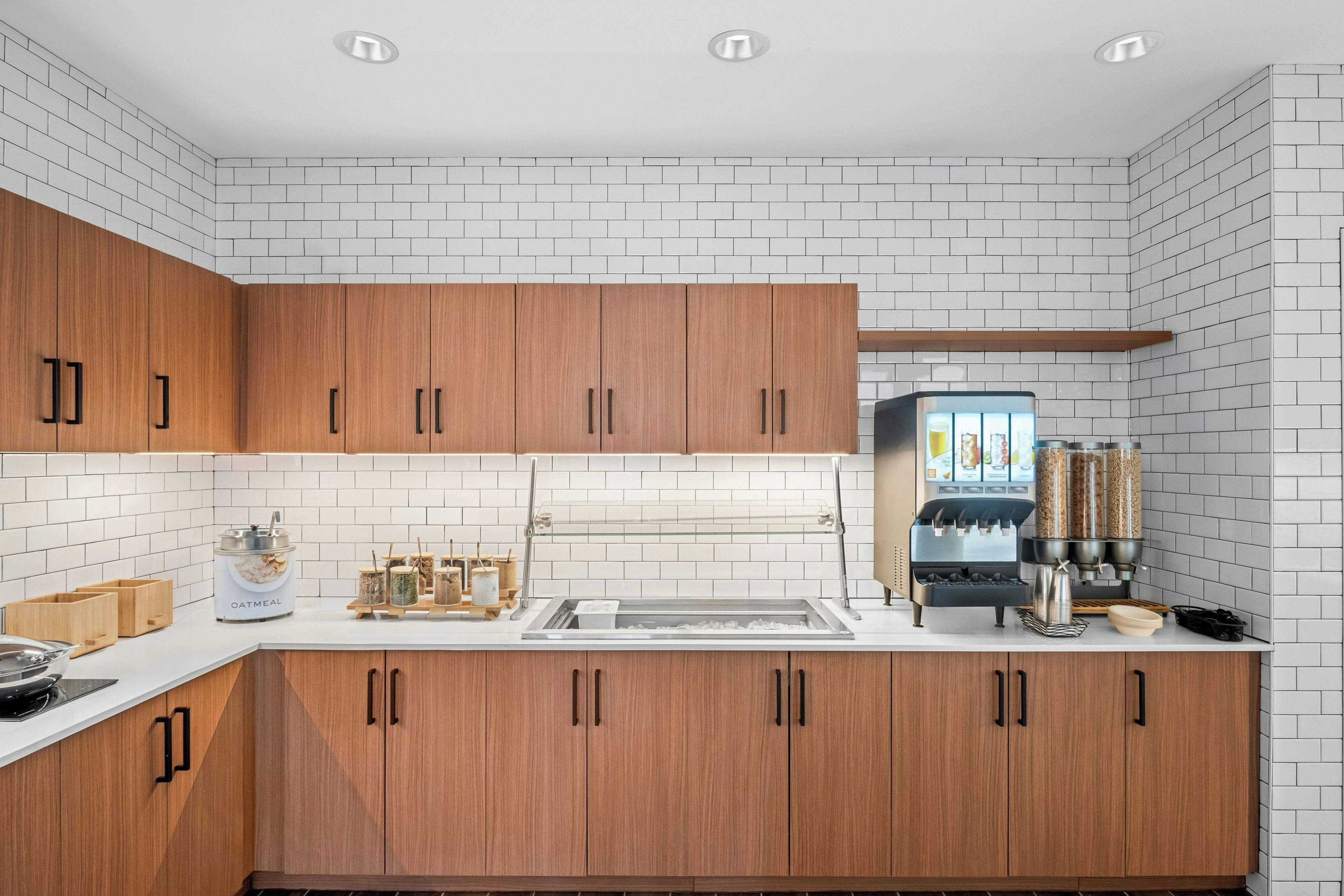 A modern kitchen with white subway tiles, wooden cabinets, and a coffee machine.