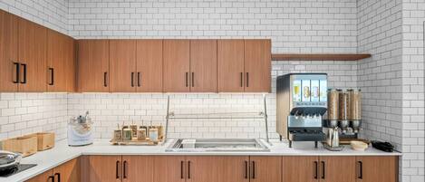 Una cocina moderna con azulejos tipo metro blancos, armarios de madera y una cafetera.