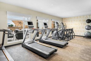 Un gimnasio con cintas de correr, pelotas de ejercicio y una pared con mensajes motivadores.