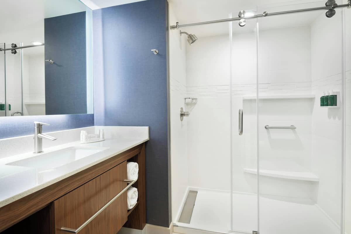 Un baño moderno con un espejo grande, lavamanos dobles y cabina de ducha con paredes de vidrio.