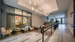 A modern hotel lobby with seating areas, a staircase, and a view of the outside. - Apartamenty Sun & Snow Rubus (Świnoujście)