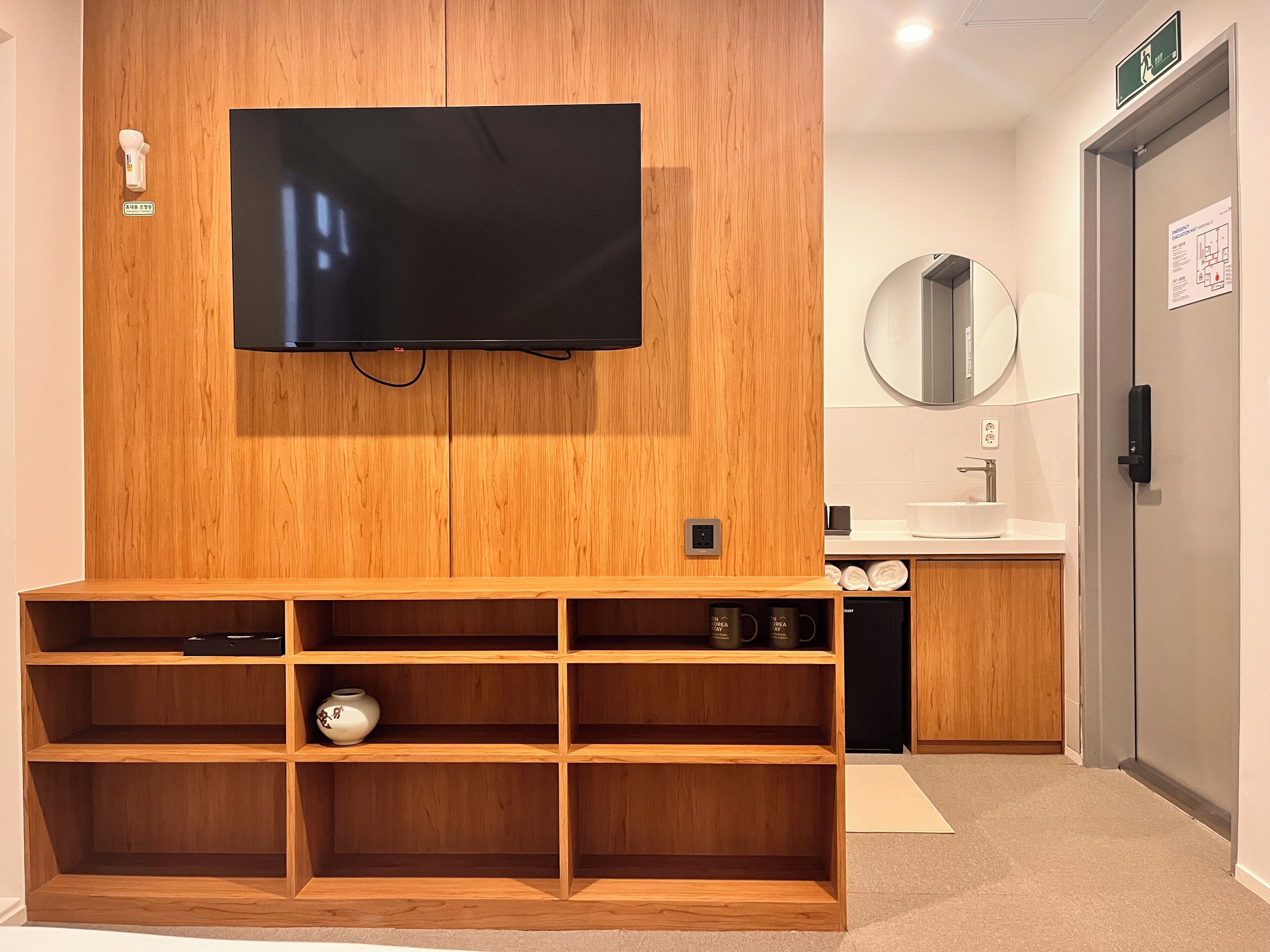 Un mueble de madera con televisor de pantalla plana, un espejo y un lavabo en un baño moderno.