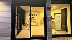 The entrance of a hotel named "On Korea Stay" with a sign indicating the address as 230-13. Inside, there are seating areas with round tables and chairs. - OnKorea Stay (Seoul)