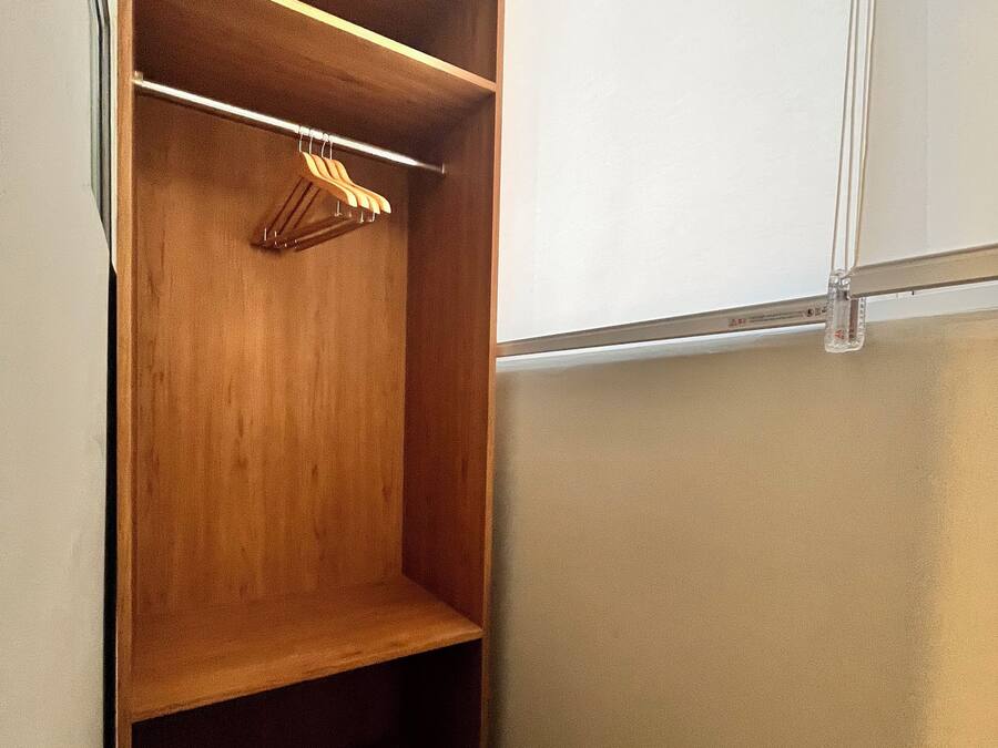 A walk-in closet with wooden shelving and a hanging rod.