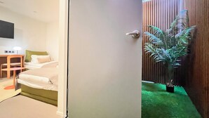 A hotel room with a bed, a desk, a chair, and a potted plant. - OnKorea Stay (Seoul)