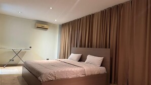 Een moderne slaapkamer met een bed, gordijnen en een airconditioning.