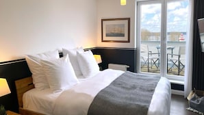 Quarto de hotel com cama, um quadro na parede, janela e vista para o exterior.