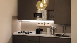 Een moderne keuken met een ingebouwde magnetron, een koffieapparaat en een spoelbak.