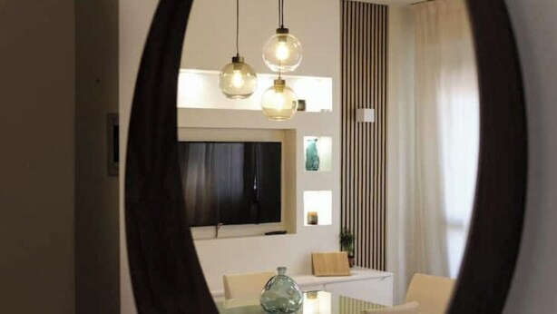 Een moderne eetruimte met een glazen tafel, witte stoelen en hanglampen.
