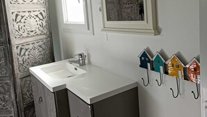 Een badkamer met een witte wastafel, twee spiegels en een decoratief wandpaneel.