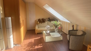 A cozy loft-style living room with a sloped ceiling, a sofa, a coffee table, and a chair.
