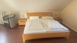 A bedroom with a wooden bed, two bedside tables, a chair, and a lamp.