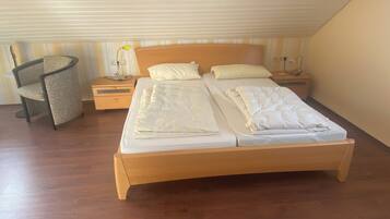 Un dormitorio con una cama de madera, dos mesitas de noche, una silla y una lámpara.