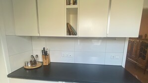 A kitchen with white cabinets, a black countertop, and a wooden utensil holder.
