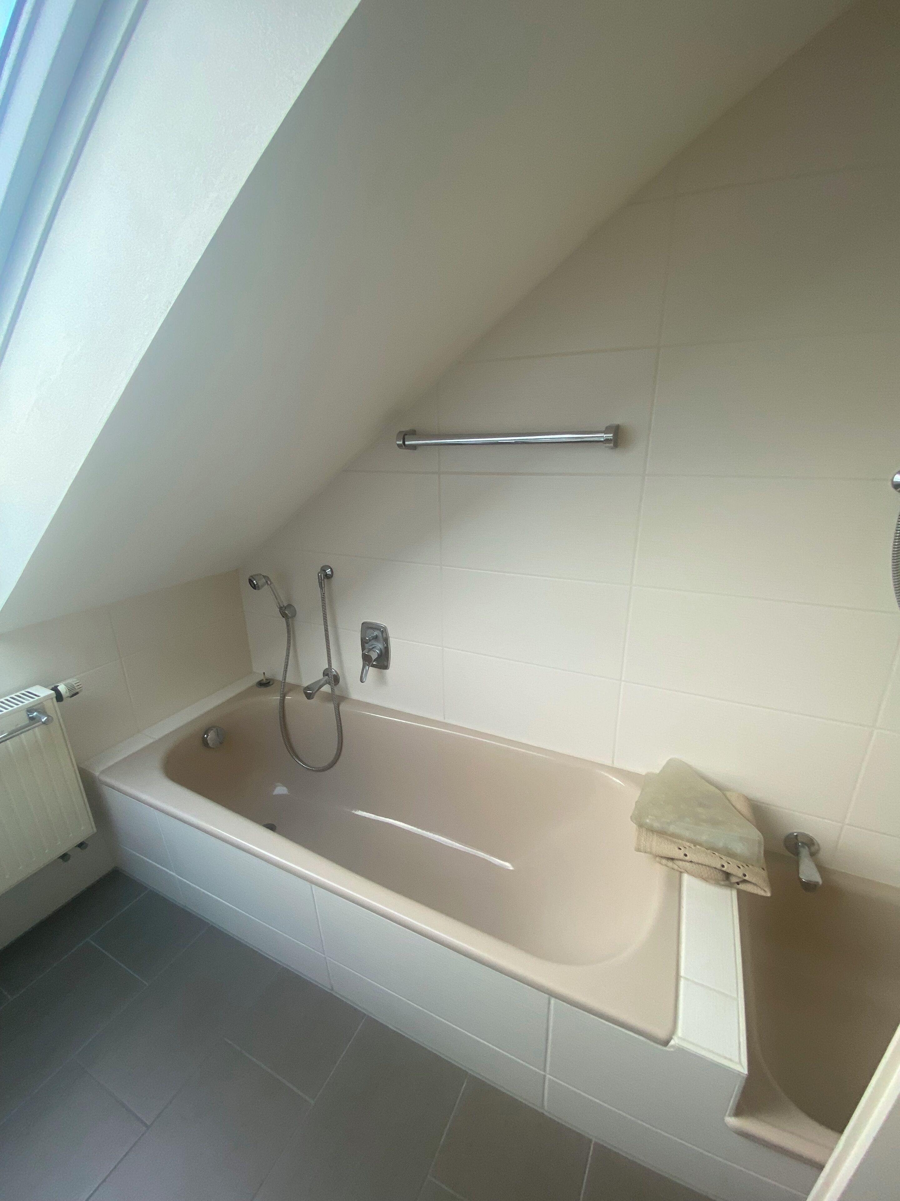 Un baño moderno con una bañera independiente, un perchero y un cabezal de ducha.