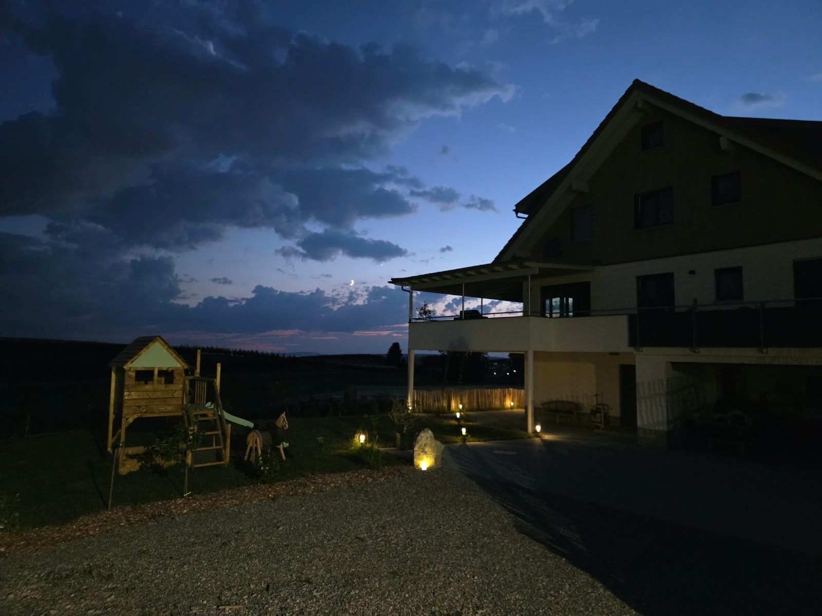 A two-story building with a covered porch and a small playhouse in the foreground.