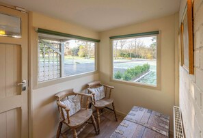 A corner room with two wooden chairs, a small table, and two windows with green frames. - Gamekeeper's Cottage at Rosebery Steading, Gorebridge (Temple)