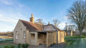 Une maison de plain-pied avec un toit en pente, un petit garage attenant et un jardin clos.