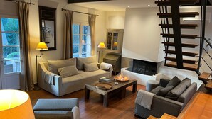 Ein modernes Wohnzimmer mit einer Couch, Sesseln, einem Couchtisch, einem Kamin und einer Treppe.