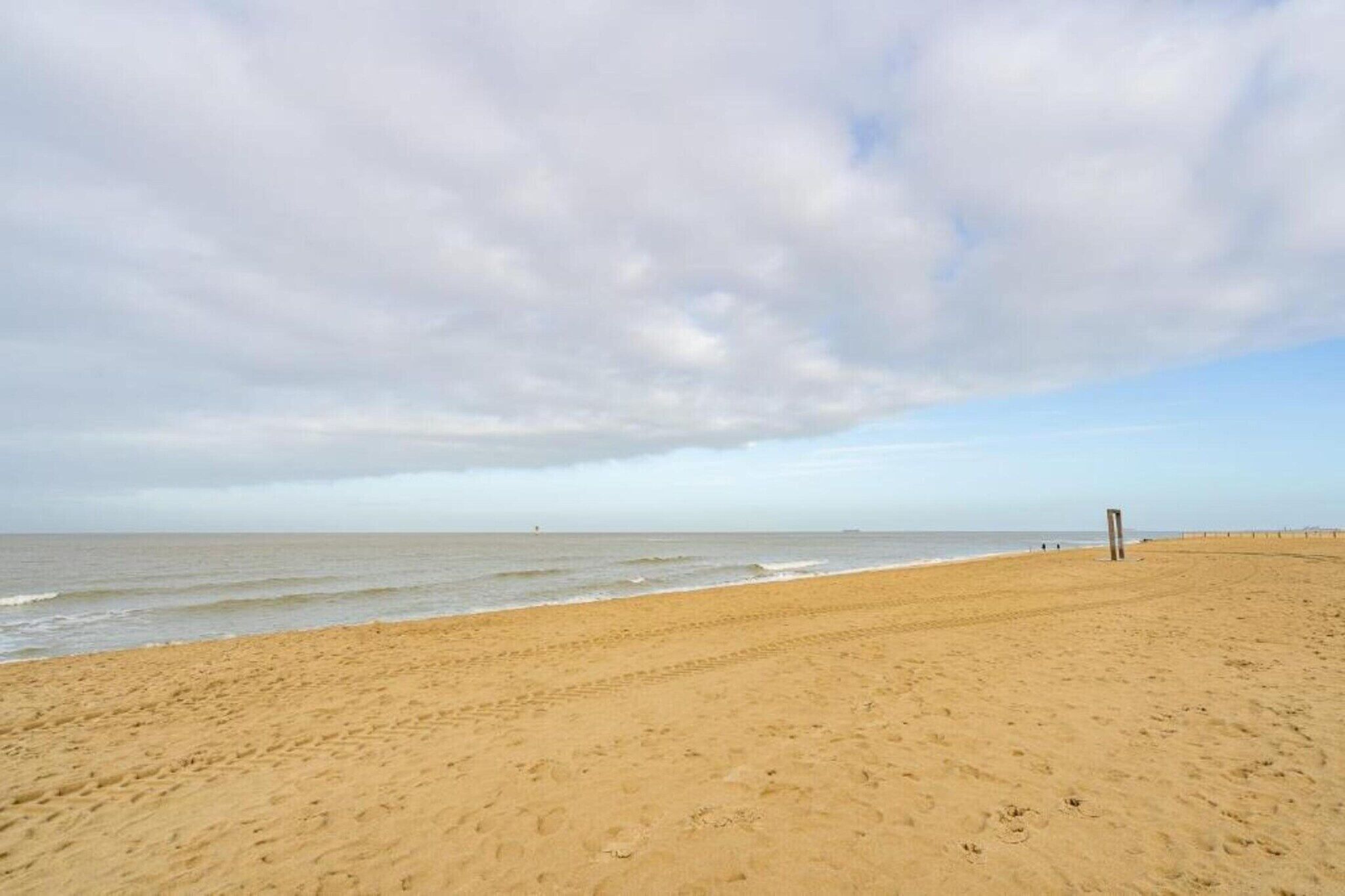 A wide sandy beach with a clear sky and a few clouds.