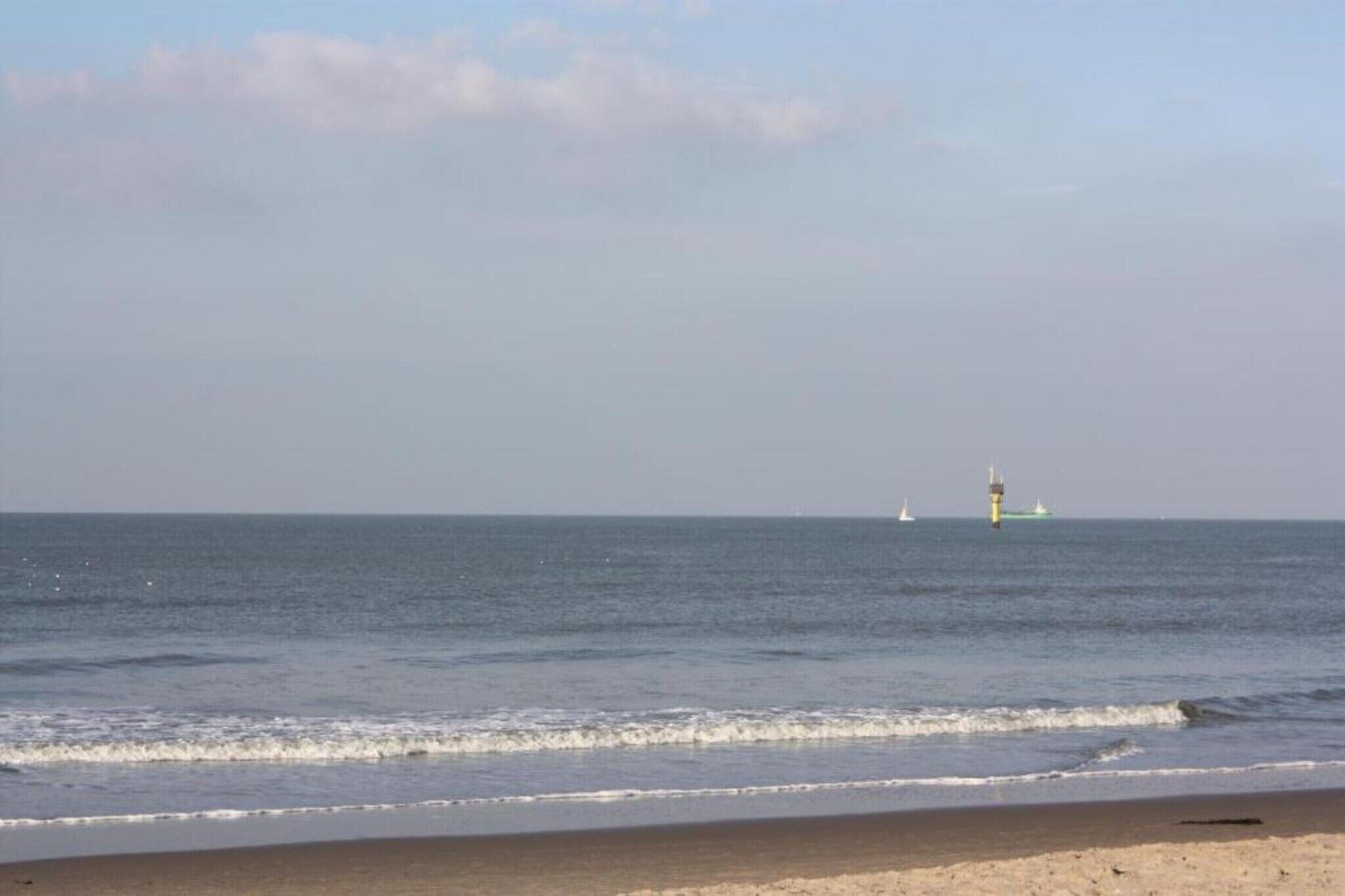 Una playa con un faro a lo lejos.