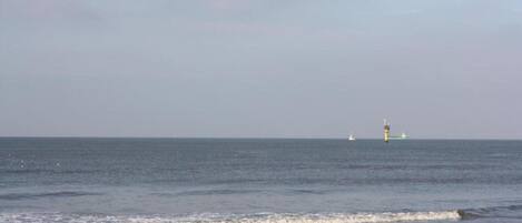 Una playa con un faro a lo lejos.