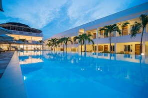 A hotel with a swimming pool, multiple balconies, and palm trees. - Palma Resort Phu Quoc, Trademark Collection By Wyn (Phu Quoc)